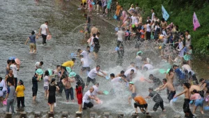 people splash water at other by river during Songkran Festival