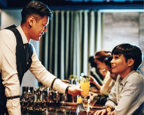 bar tender serving drinks to female asian guests