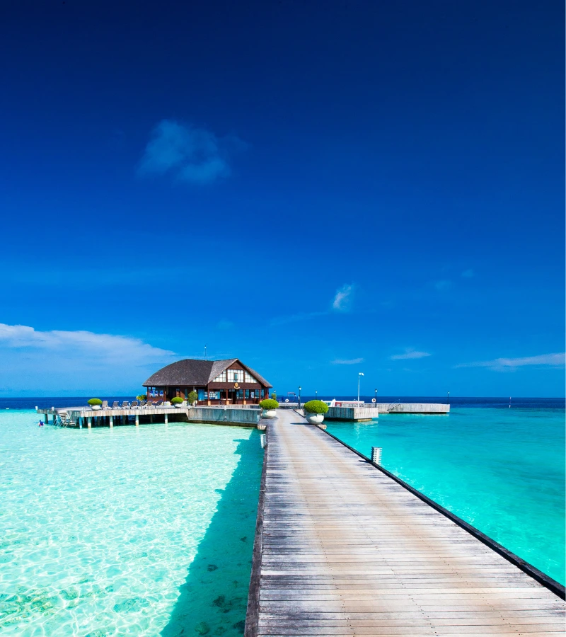 overwater bungalow in crystal clear water and under blue sky in Maldives