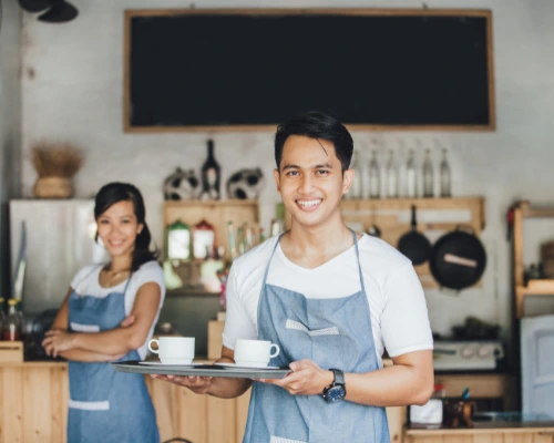 waiter serving coffee while waitress smiles at the back